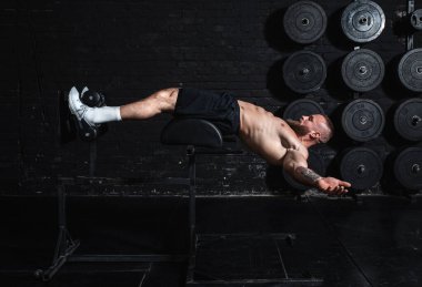 Genç, aktif, terli, formda, kaslı, kaslı, aktif bir adam. Spor salonunda karın kasları çalıştırıyor.