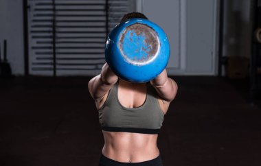 Genç, terli, kaslı, formda, elinde ağır bir kettlebell tutan ve spor salonunda sıkı antrenman yapan gerçek insanlar seçici odaklanma bulanıklığı yaşıyor.
