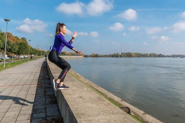 Genç, terli, aktif, seksi, formda, kaslı, kaslı bir kadın. Bir diziyle duvara tırmanıyor. Açık havada vücut ağırlığı ile hareket bulanıklığı ile egzersiz yapıyor.