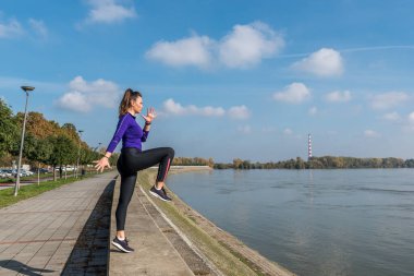 Genç, terli, aktif, seksi, formda, kaslı, kaslı bir kadın. Bir diziyle duvara tırmanıyor. Açık havada vücut ağırlığı ile hareket bulanıklığı ile egzersiz yapıyor.