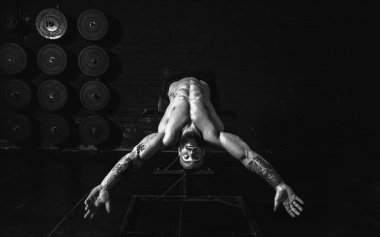 Genç, aktif, terli, formda, kaslı, kaslı, aktif bir adam spor salonunda karın kasları çalıştırıyor.