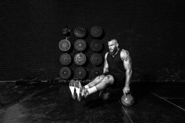 Genç, aktif, terli, güçlü, kaslı, kaslı, kaslı bir adam. Sert karın kasları çalıştırıyor. Bacakları spor salonundaki iki su ısıtıcısının üstünde.