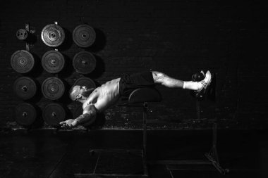 Genç, aktif, terli, formda, kaslı, kaslı, aktif bir adam spor salonunda karın kasları çalıştırıyor.