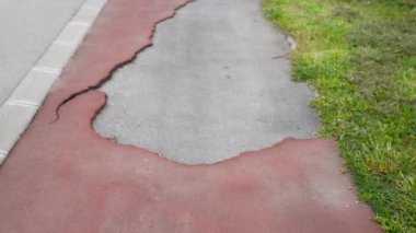 Damaged red tartan running track surface with hole and damage from the low quality selective focus