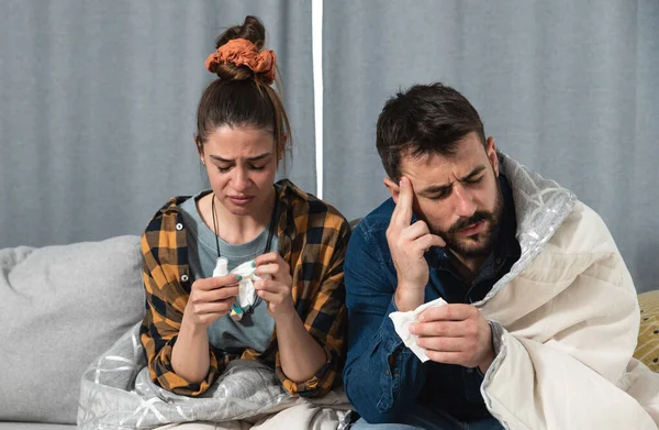 一对患有感冒和流感的年轻夫妇坐在家里 裹着毛毯 一边用纸巾擦拭鼻子 一边头疼得厉害 — 图库照片
