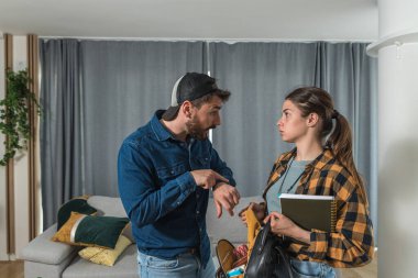 Genç bir çift tartışıyor çünkü kadın cüzdanından arabasını ya da evinin anahtarlarını kaybetmiş ve bir erkeğin el hareketi, çılgın bir yüz ifadesi yüzünden geç kaldıklarını gösteriyor.