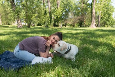 Genç ve güzel bir kadın, güneşli ve güzel bir günde köpeğiyle parkta altın Labrador Retriever oynuyor ve eğleniyor.