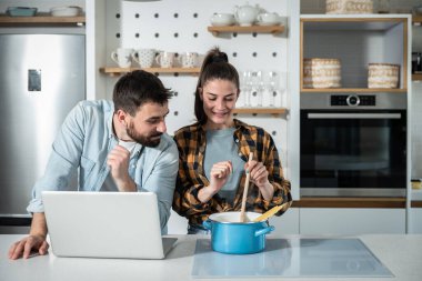 Mutfaktaki genç mutlu çift kız arkadaşına sataşıyor. Bilgisayara ihtiyacı olduğunda nasıl yemek pişireceğini ve internetten internet tarifleri kullanacağını bilmiyor.