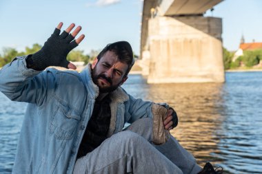 Depresyonda olan alkolik evsiz bir adam köprünün altında oturup alkol içerek uyuduktan sonra yüzünü güneş ışığından korumaya çalışıyor ve daha fazla içmek için uyanıyor, sosyal belgesel.