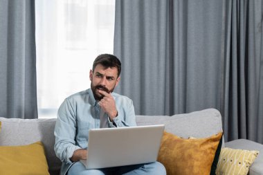 Genç, mutlu, serbest çalışan bir iş adamı dizüstü bilgisayarıyla yeni projesi için müşteri şirketinden yeni fikirler ve çözümler bulmaya çalışıyor. 