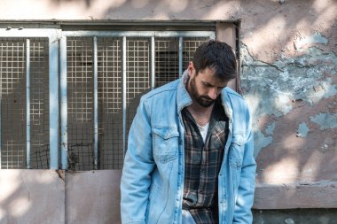 Toplum tarafından terk edilmiş, çaresiz ve bunalımda olan genç bir evsiz. Binaya yaslanmış, sosyal belgesel konsepti.