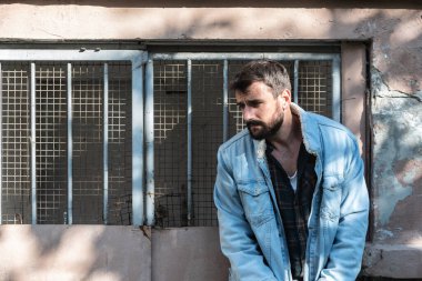 Genç, aç, hasta ruhlu, ruhsal dengesi bozuk evsiz bir adam sokakta çaresiz ve ümitsiz bir şekilde duruyor.