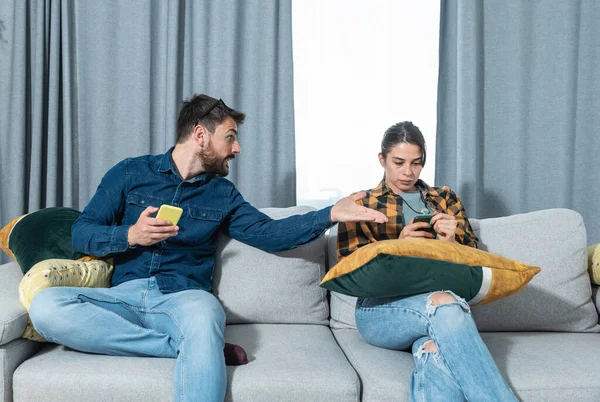 Evde oturan genç çiftin, sosyal medya ağları aracılığıyla akıllı telefonlarda sohbet ve flörtleşmenin yol açtığı kıskançlık, ilişki sorunları ve güvensizlik nedeniyle sorunları var ve tartışıyorlar.
