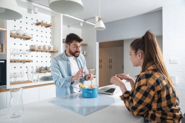 Genç mutlu çift mutfakta durup yemek pişiriyor. İnternette buldukları tarifleri kullanıyorlar.