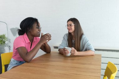 Bir web geliştirme şirketinde çalışan iki genç bayan bir siyah ve beyaz kadın kahve molası verip özel hayatları ve şirketin geleceği ve işi hakkında konuşuyorlar.