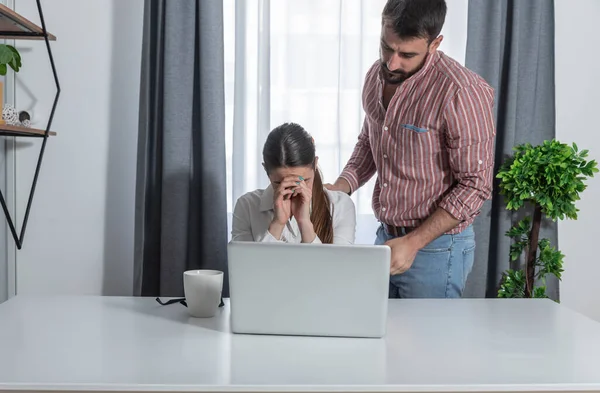 Young woman worker made a mistake in the program on the computer and is very upset and a male colleague comforts her because she will correct the mistake