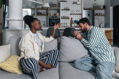 Genç siyahi kadın sigara içilmesine ve sigara içilmemesine karşı olduğu için beyaz erkek arkadaşı sigara yakarken mutsuz. 