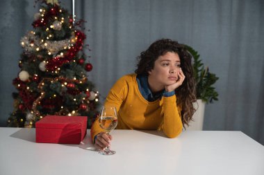 Genç üzgün kadın Noel ağacının önünde tek başına oturuyor ve şampanya içiyor. Çünkü ilk kez tatilde yalnız kalıyor. Kocası ya da nişanlısı orduda asker.