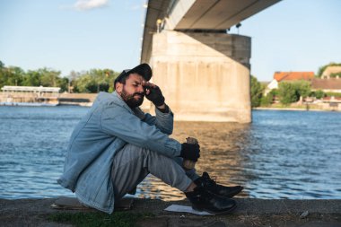 Genç, üzgün ve bunalımlı bir adam nehir kenarında oturmuş alkol içiyor, kendini perişan hissediyor ve dünyadan ve aileden terk edilmiş hissediyor.