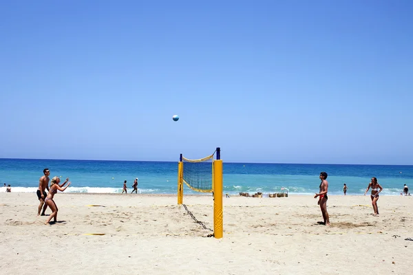 Giovani turisti che giocano a pallavolo sulla spiaggia sabbiosa di Creta, G — Foto Stock