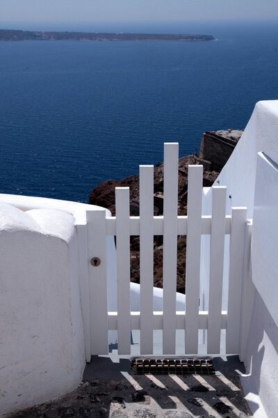 Small white fence gate and sea view on Santorini island, Greece.