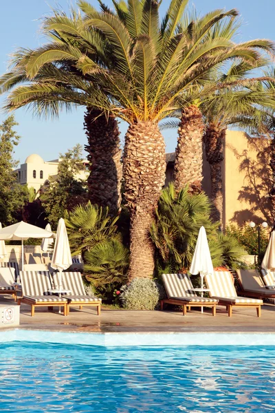 Hôtel Resort avec chaises longues, palmiers et piscine — Photo