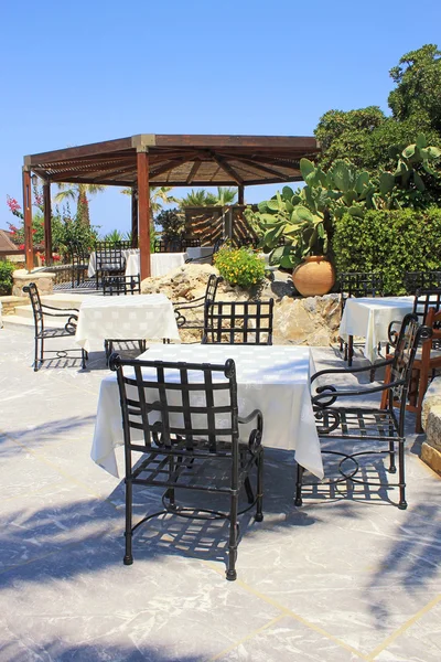 Tafels en ijzeren stoelen op terras en mooie tuin, Kreta, Griekenland — Stockfoto