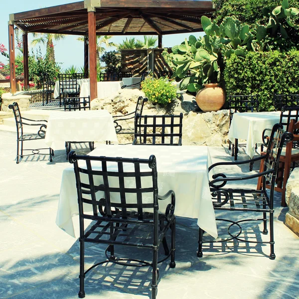 Mesas e cadeiras de ferro no terraço e belo jardim, Creta, Grécia — Fotografia de Stock