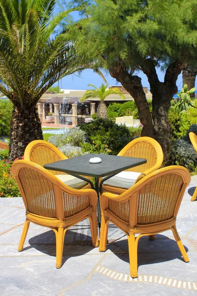 Rieten stoelen en palmbomen in het mediterrane hotel, Crete, — Stockfoto