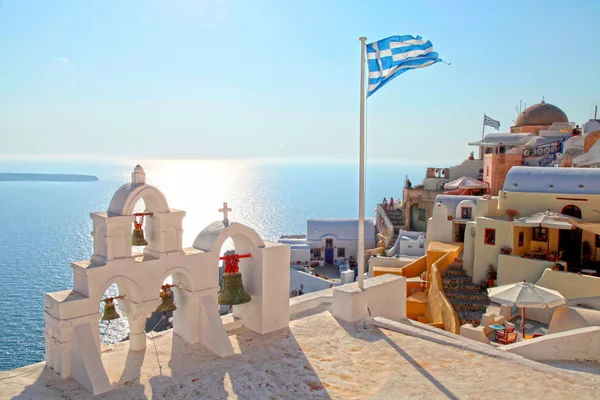 Griechische flagge und glockenturm in oia village, santorini, griechenland lizenzfreie Stockfotos