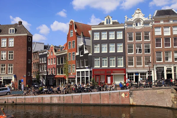 Люди в уличных кафе и старых домах вдоль канала в Амстердаме — стоковое фото
