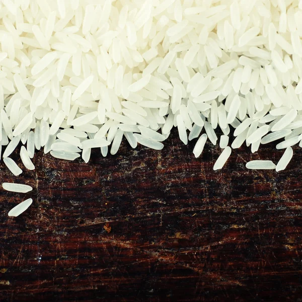 Ahşap tahta üzerinde beyaz çiğ pirinç tahıl — Stok fotoğraf