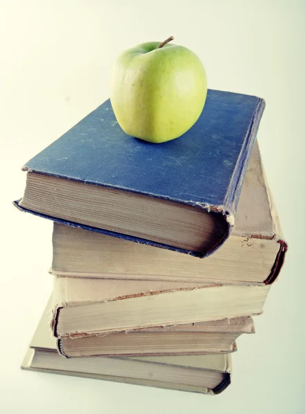 Pila di vecchi libri con copertina rigida con mela verde — Foto Stock