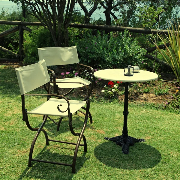 Table and iron chairs on green grass in the garden