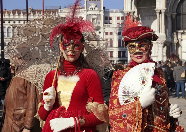 Gemaskerde vrouwen in rood kostuum op het San Marco plein, Venetië — Stockfoto