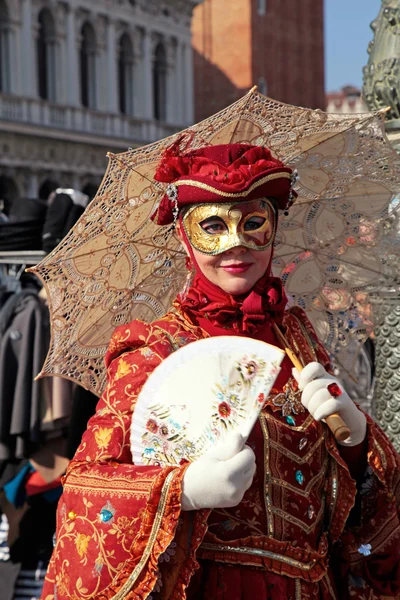 Μασκοφόροι γυναίκα στο κόκκινο κοστούμι με ομπρέλα και ανεμιστήρα, Βενετία — Φωτογραφία Αρχείου