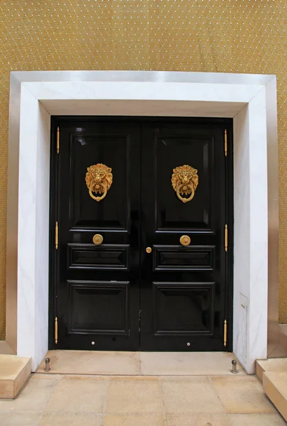 真鍮のライオン、モナコの形状のノブ付き黒の木製ドア — ストック写真