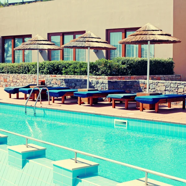 Junto a la piscina con cama de piscina y sombrilla en un resort de lujo —  Fotos de Stock