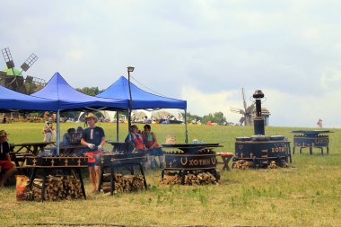 Man cooking hot street food on the huge grill outdoor pan, Pirogovo,Kiev