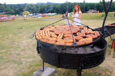 Cooking traditional sausages on grill outdoor pan in Museum Pirogovo, Kiev