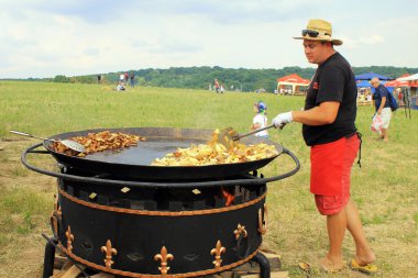 Man cooking crisp potato on the huge grill outdoor pan, Pirogovo, Kiev