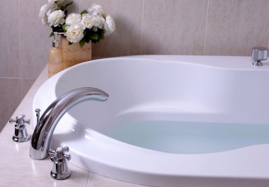 White bath tub with faucet and mosaic tiles