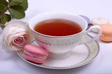 Cup of tea with pink french macaron and pastel rose
