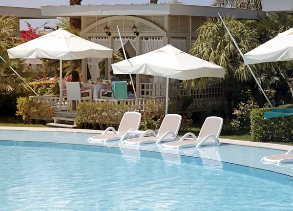 Camas de sol na piscina para relaxar na bela estância de verão — Fotografia de Stock