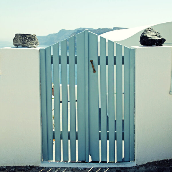 blue wooden gates in white house, Santorini island, Greece