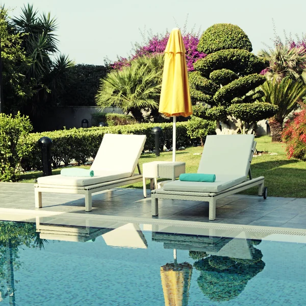 White outdoor furniture and yellow umbrella near resort swimming Stock Kép