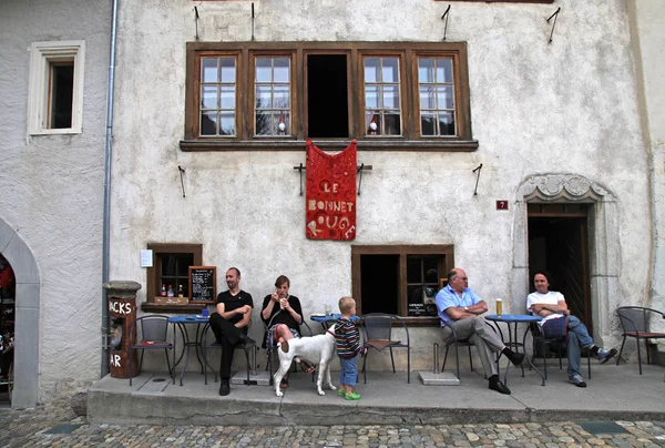 Ludzi w tradycyjnych kawiarni w szwajcarskiej miejscowości Gruyères, Switzerland. — Zdjęcie stockowe