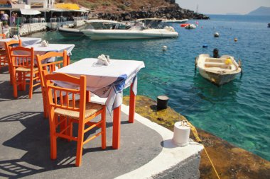 Deniz sahilinde, Yunanistan turuncu ahşap sandalye ile Yunan tavernası