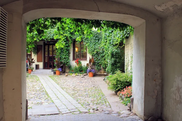 Arch in oude dorpswoning, kleine tuin en bloemen — Stockfoto