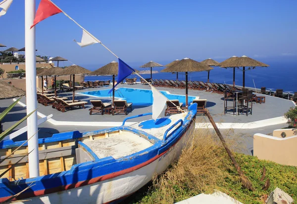 Старая рыбацкая лодка, шезлонги и бассейн на террасе над Средиземным морем — стоковое фото